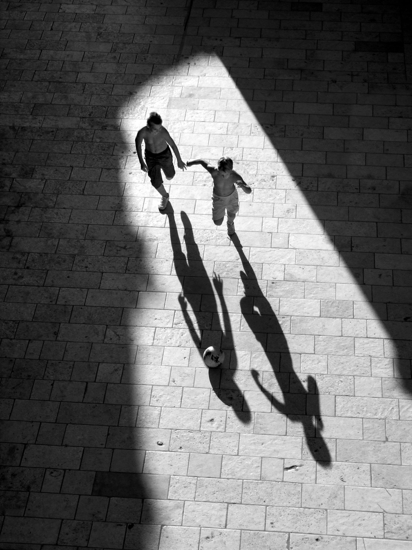 Two figures crossing a striped plaza, seen from above