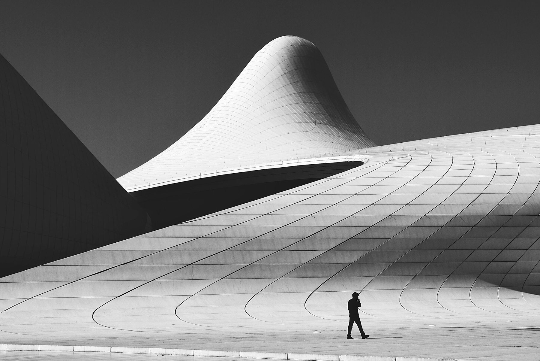 A lone figure walking towards light through curved white architecture